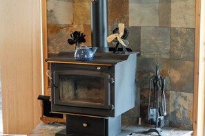 A wood-burning stove with a glass door, a kettle on top, and a chimney. - Waterfall Retreat at Peppermint Falls (Springville)