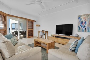 A modern living room with a sofa, coffee table, TV, and artwork. - 3 Bedroom Oceanfront Rooftop (Kings Beach)