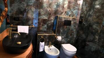 A bathroom with a black sink, a bidet, and a toilet.