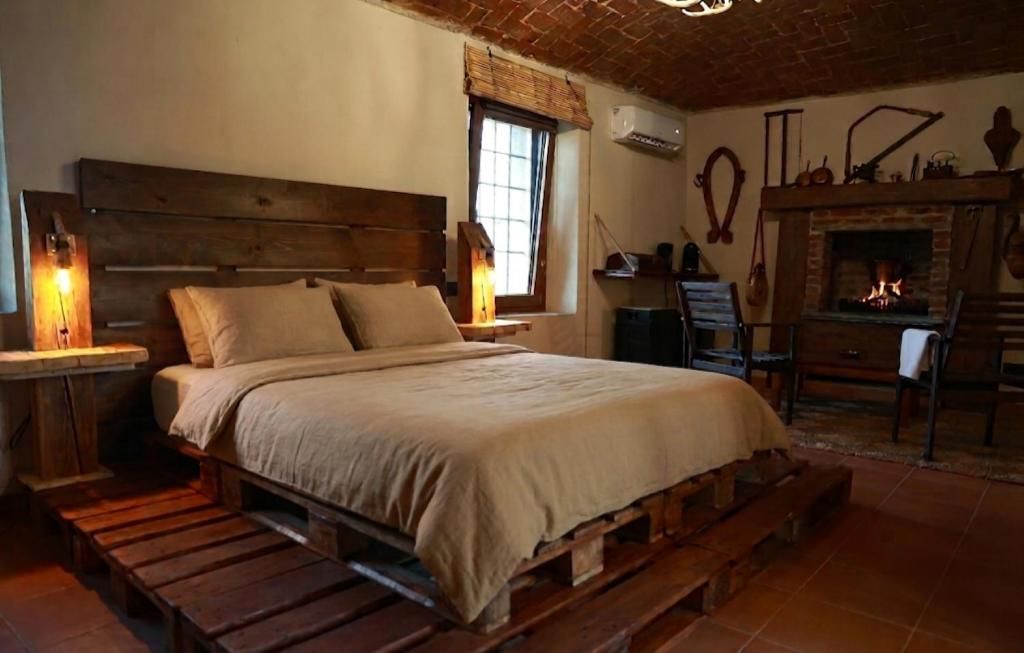 A rustic bedroom with a wooden bed, a fireplace, and a window with a view.
