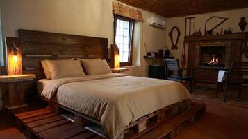 A rustic bedroom with a wooden bed, a fireplace, and a window with a view.