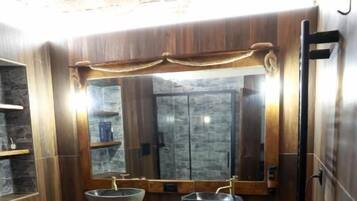 Une salle de bain avec un meuble-lavabo en bois, deux vasques, un grand miroir et une serviette accrochée au mur.