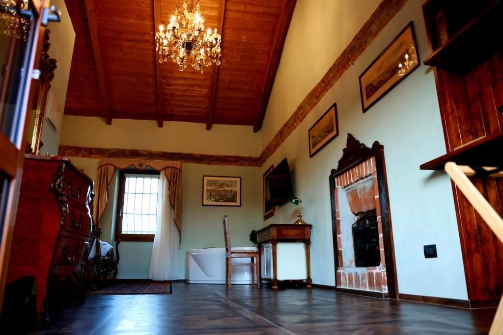 A room with a wooden ceiling, a chandelier, a fireplace, and a large window.