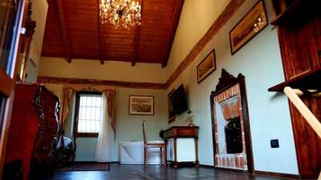 A room with a wooden ceiling, a chandelier, a fireplace, and a large window.