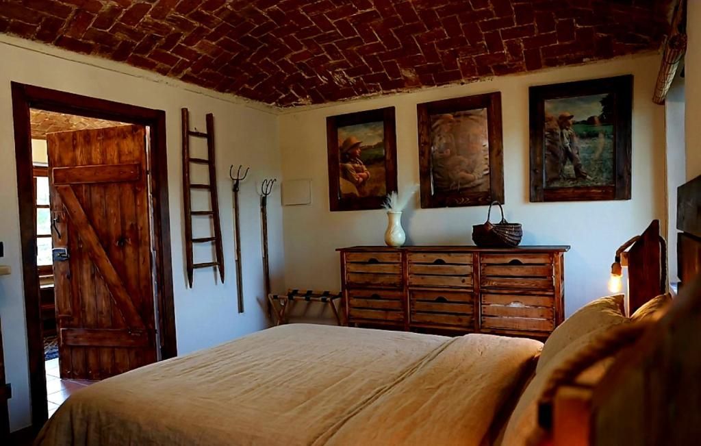 Una habitación con cama, cómoda de madera y cuadros en la pared.