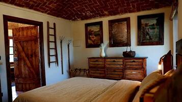 Una habitación con cama, cómoda de madera y cuadros en la pared.