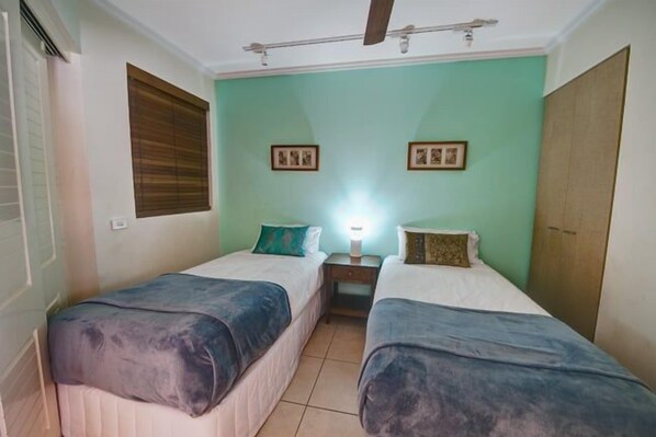 A room with two beds, a nightstand, a ceiling fan, and a window with blinds. - 2 Bedroom Oceanfront Rooftop (Kings Beach)