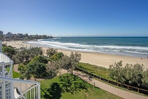 A coastal view with a beach, ocean, and a pathway leading to a building with a balcony. - 2 Bedroom Oceanfront Rooftop (Kings Beach)