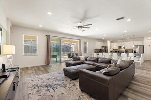 A spacious living area with a sectional sofa, a flat-screen TV, and a dining table with chairs. - Ping-pong | Basketball | Game Room | Resort-Style Pool: Golden Palms Retreat (Davenport)