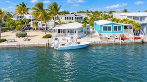 A waterfront property with a boat docked, a pool area, and multiple houses with balconies. - Upscale Oceanfront Retreat - 47' Seawall, Boats up to 44', Sleeps 6 & Pet Friendly! (Cudjoe Key)