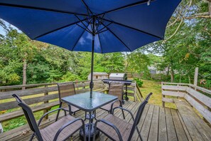 An outdoor patio with a table and chairs, a barbecue grill, and a wooden deck. - Bayside Burrow - Cape home near beaches (Brewster)