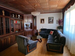 Un soggiorno tradizionale con mobili in legno, un lampadario e opere d'arte alle pareti.