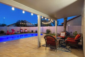 A covered patio with a swimming pool, outdoor furniture, and string lights. - Private Pool | Game Room | Mesa Family Retreat (Mesa)
