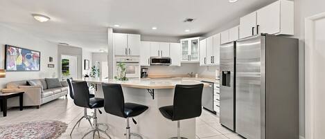 A modern kitchen with a central island, stainless steel appliances, and a seating area with bar stools.
