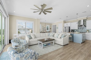 A spacious living room with a large sofa, a coffee table, and a patterned armchair. - Beachside Bliss with Heated Pool, Spa, Bikes & Views - Cozy Cottage - Roelens (Fort Myers Beach)