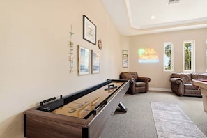 A room with a foosball table, a pool table, two leather sofas, and a neon sign reading 'Palm Villa GAMEROOM'. - Waterfront Fun, Pool & Spa Paradise with Game Room & Gulf Access - Palm Vista Villa - Roelens (Cape Coral)