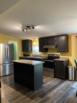 A modern kitchen with dark cabinetry, stainless steel appliances, and a central island.