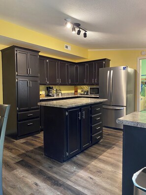 A kitchen with dark cabinets, a stainless steel refrigerator, and a granite countertop.