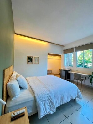 A bedroom with a bed, desk, chair, and a window. - Herbolaria Hotel (San Salvador)