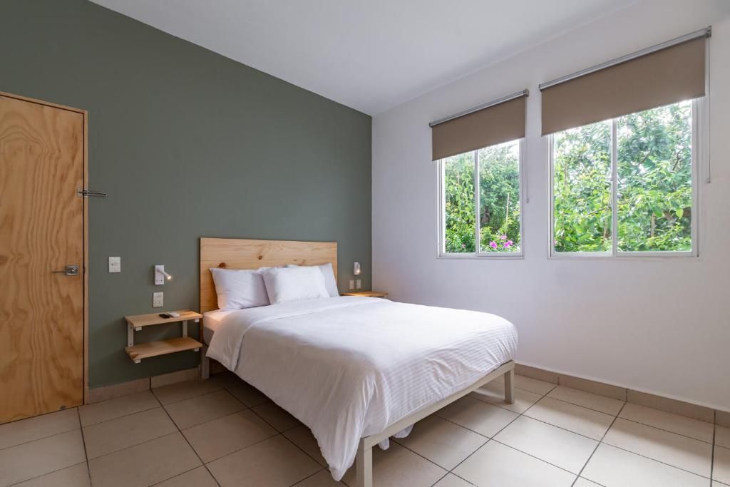 Un dormitorio con cama, mesita de noche, puerta de madera y ventanas con persianas.