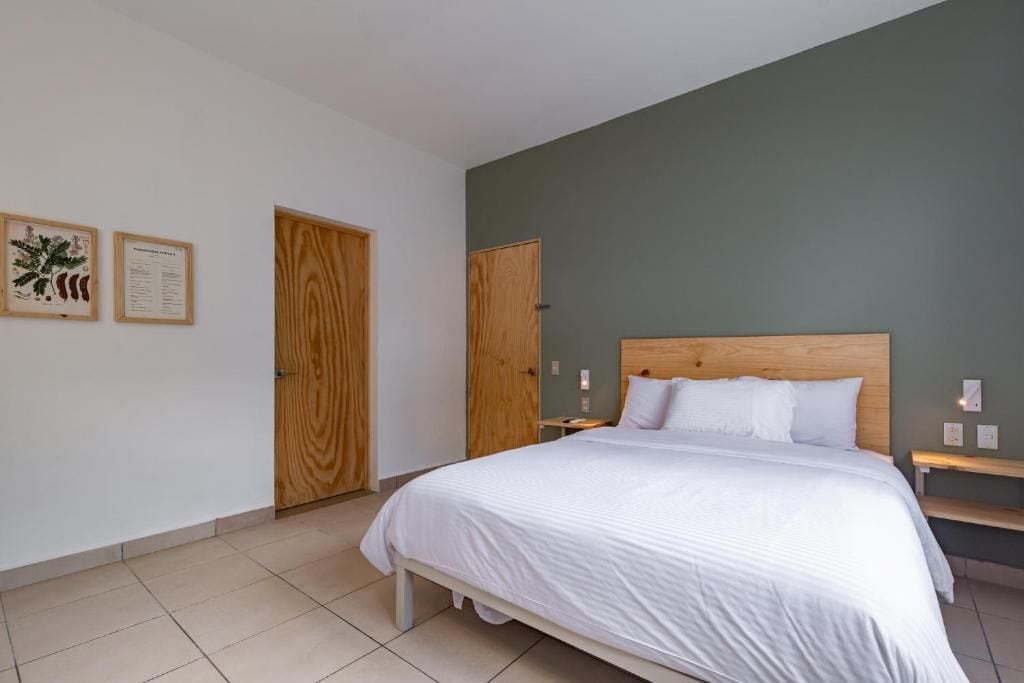 A bedroom with a bed, wooden headboard, white bedding, two wooden doors, and a wall-mounted light fixture.