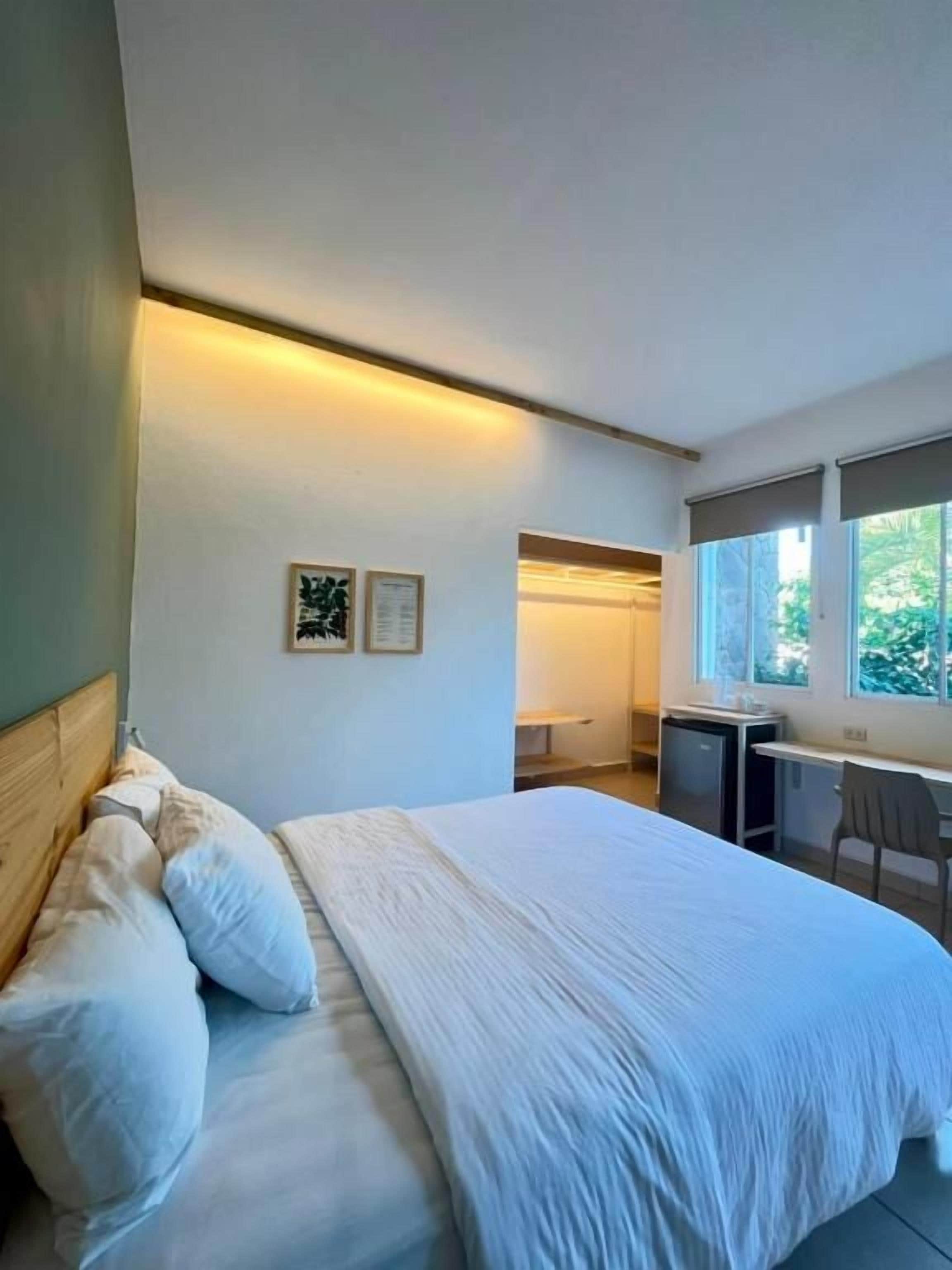 A hotel room with a bed, a desk, a chair, and a window.