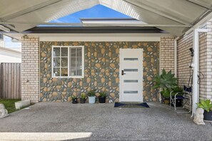 A house with a stone facade, a white door, and a covered porch with potted plants. - Sunnybank Hills Escape | 2BR Near Sunnybank Plaza (Sunnybank Hills)