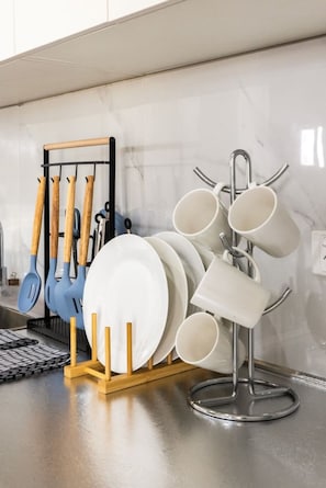 Een keuken met een messenbord vol houten gereedschap en een muggenrek met witte mokken.