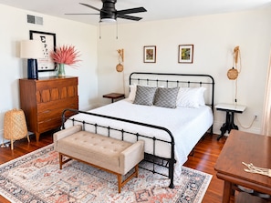 Un dormitorio con cama, cómoda, banco y una pequeña mesa.