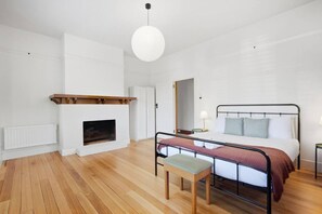 A bedroom with a bed, bedside tables, a fireplace, and a hanging light fixture. - Spacious New Town Family Retreat (New Town)