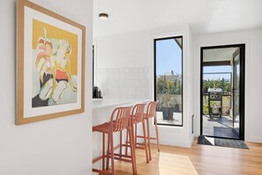 A modern kitchen with a dining area, a large window, and a sliding door leading to an outdoor patio. - Spacious New Town Family Retreat (New Town)