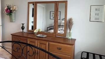 Une chambre à coucher avec un lit, une commode, un miroir et une table de chevet.