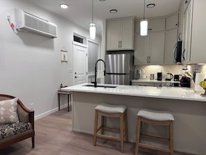 A modern kitchen with a stainless steel refrigerator, white cabinetry, and pendant lighting.