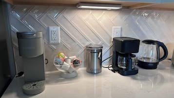 Une cuisine équipée d’une machine à café, d’une bouilloire et d’une cafetière sur le plan de travail.
