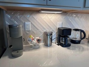 Een keuken met een koffiezetapparaat, een waterkoker en een koffiekan op het aanrecht.
