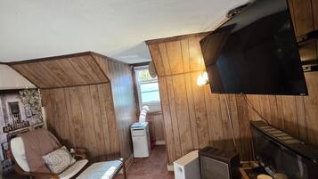 A compact living space with a television, a small kitchenette, and a seating area with a chair and a sofa.