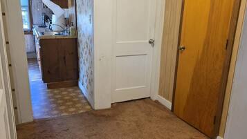 A hallway with a carpeted floor, a white door, and a wooden door.
