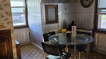 Un coin repas avec une table ronde, des chaises et une horloge au mur.