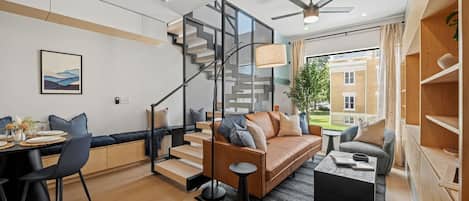 A modern living room with a staircase, a dining area, and a view of the outside.