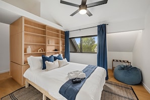 A bedroom with a bed, a large wardrobe, a ceiling fan, and a window with curtains. - 3-Story Designer Townhome by City Park (Manhattan)