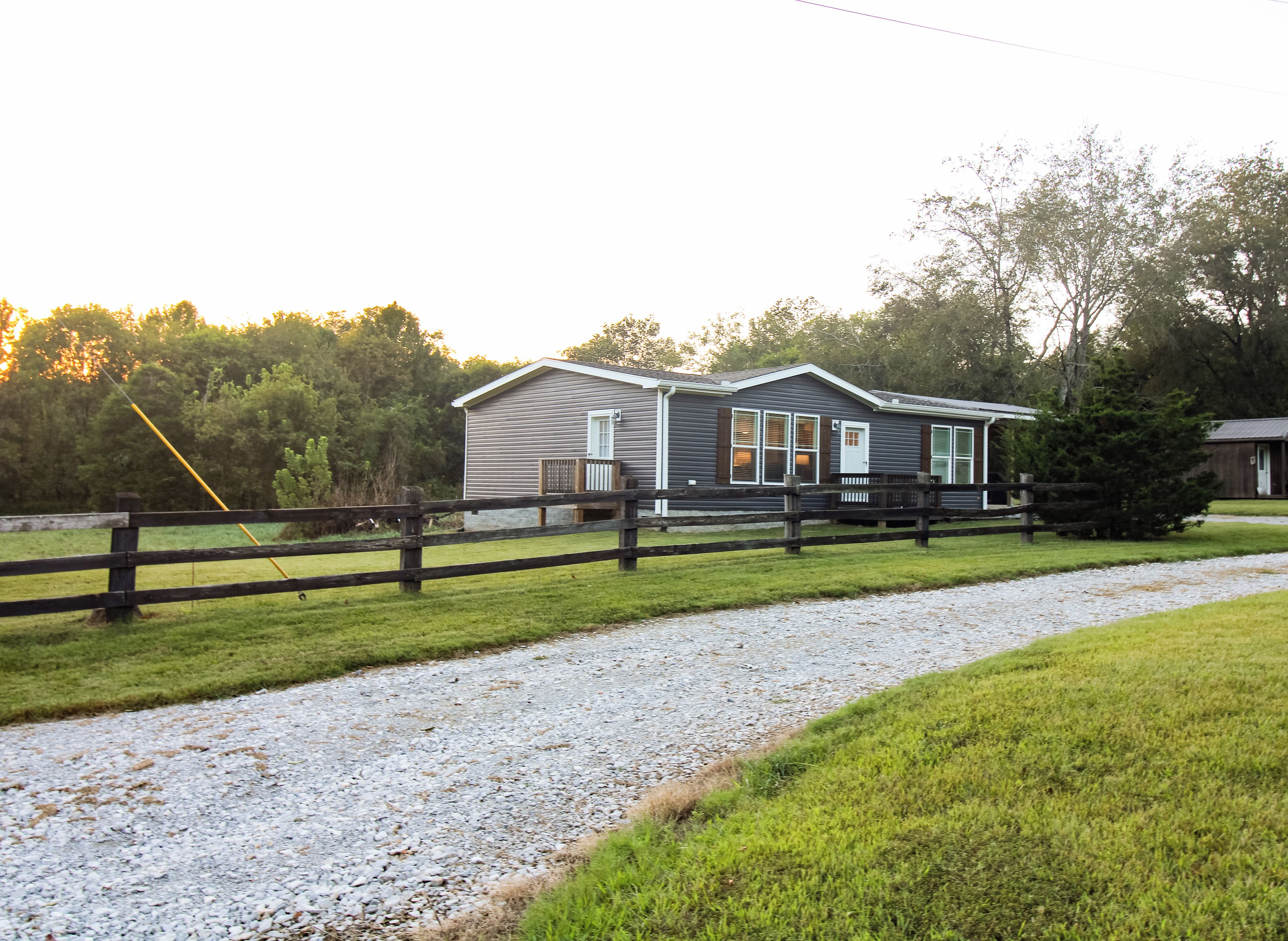 A two-story building with a gravel driveway and a wooden fence.