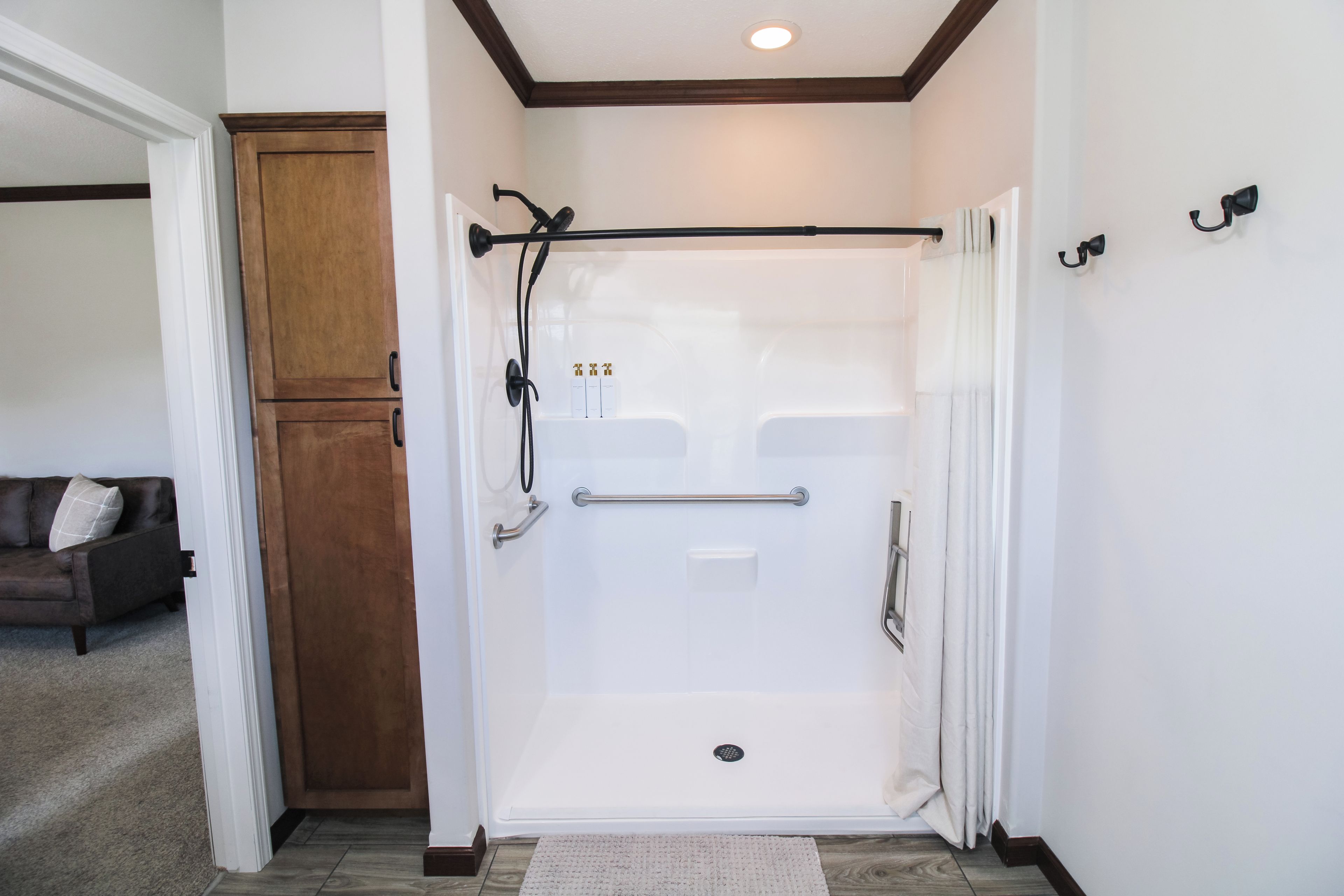 A walk-in shower with a glass door, a handrail, and a showerhead.