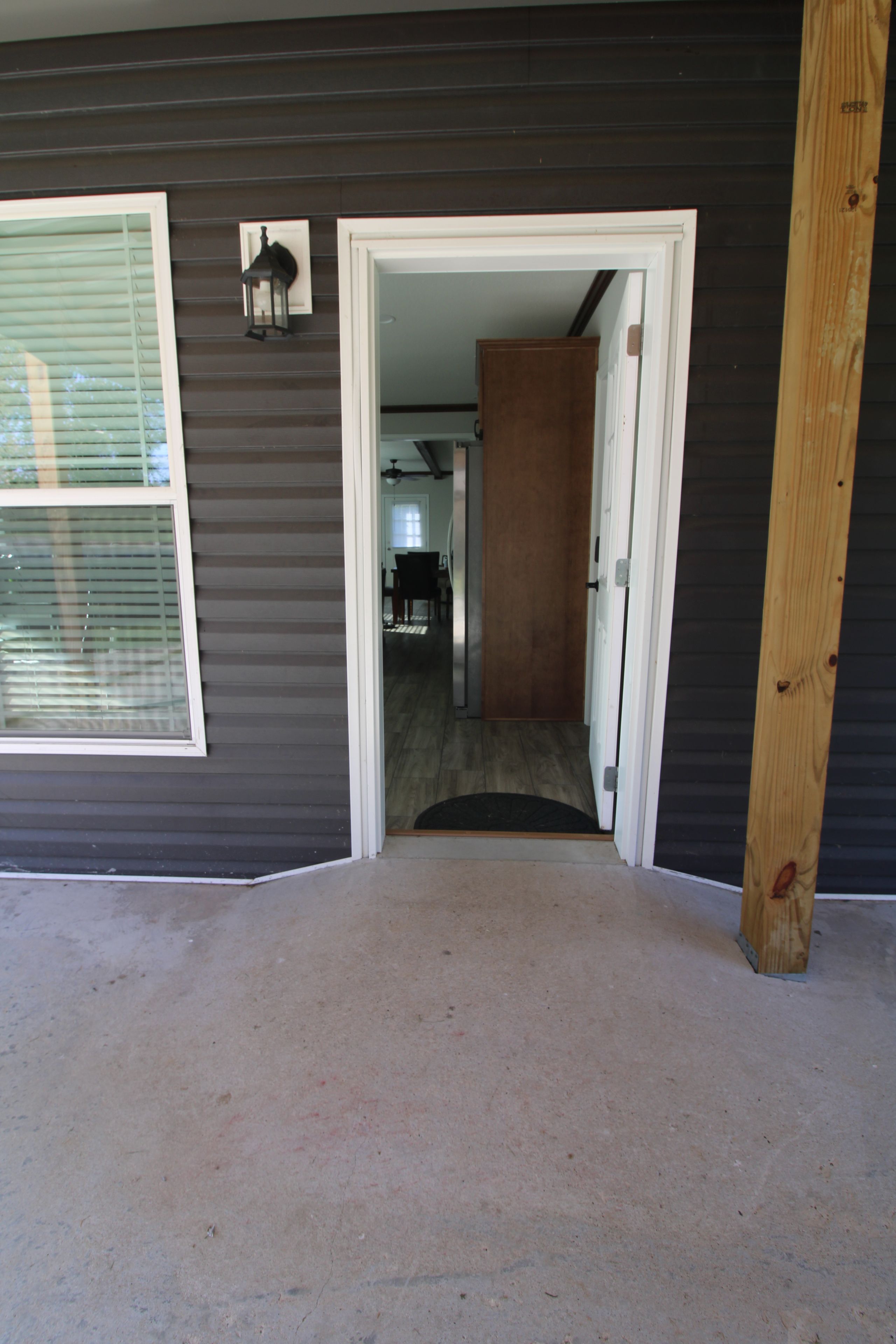 A hallway leading to a dining area with a ceiling fan, a door, and a window with blinds.