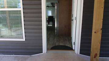 A hallway leading to a dining area with a ceiling fan, a door, and a window with blinds.