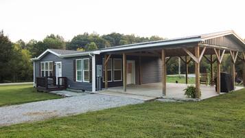 Ein zweistöckiges Haus mit überdachter Veranda und einem umzäunten Garten.