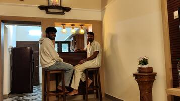 A room with a ceiling fan, a wooden table, and two people seated.