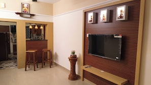 A living room with a TV, wooden furniture, and a decorative shelf. - Your boutique holiday home in Fort Kochi. Operated by Costa Gama, (Kochi)