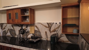 A kitchen with wooden cabinets, a black countertop, and a patterned backsplash. - Your boutique holiday home in Fort Kochi. Operated by Costa Gama, (Kochi)