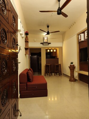 A living room with a sofa, a ceiling fan, and a wooden cabinet with decorative elements. - Your boutique holiday home in Fort Kochi. Operated by Costa Gama, (Kochi)