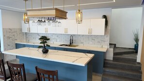 Et moderne køkken med marmorbordplade, en central ø og et bonsaitræ.